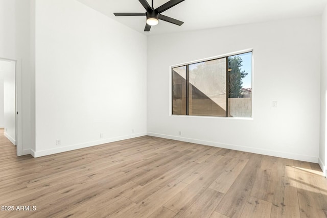 spare room with light wood-style floors, lofted ceiling, ceiling fan, and baseboards