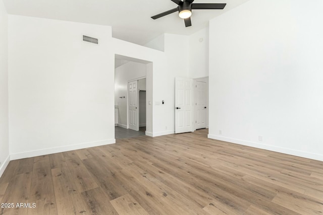 unfurnished bedroom with visible vents, a ceiling fan, wood finished floors, high vaulted ceiling, and baseboards