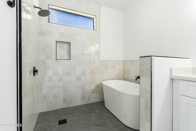 bathroom featuring tile walls, vanity, a freestanding tub, tiled shower, and tile patterned floors