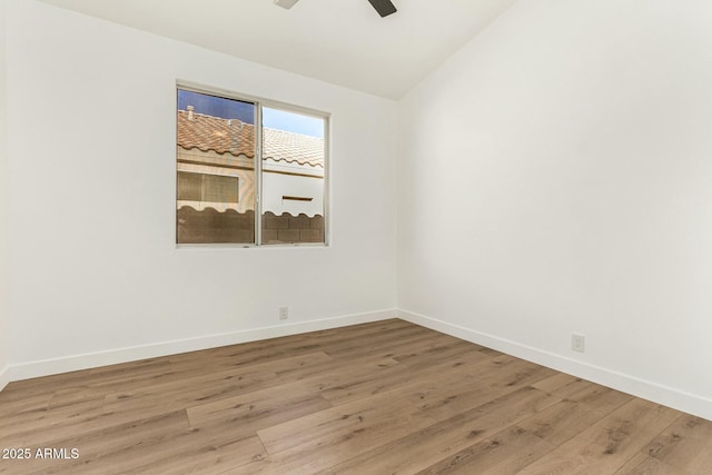 spare room featuring lofted ceiling, wood finished floors, a ceiling fan, and baseboards