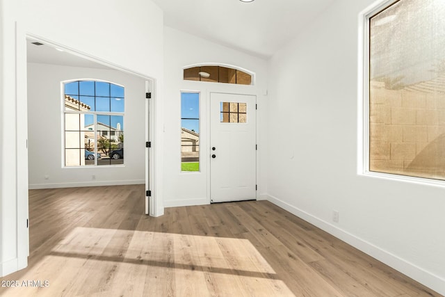 entrance foyer featuring baseboards, vaulted ceiling, and wood finished floors