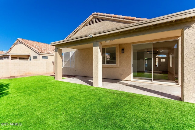 rear view of house featuring a yard, a patio, stucco siding, fence, and a tiled roof