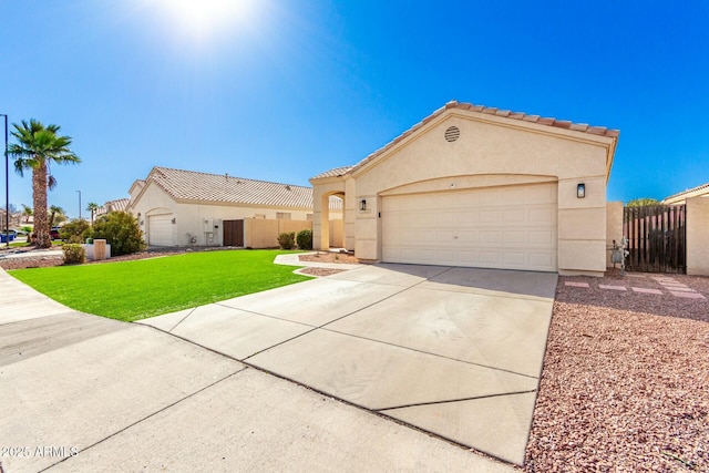 mediterranean / spanish house with concrete driveway, a front lawn, fence, and stucco siding