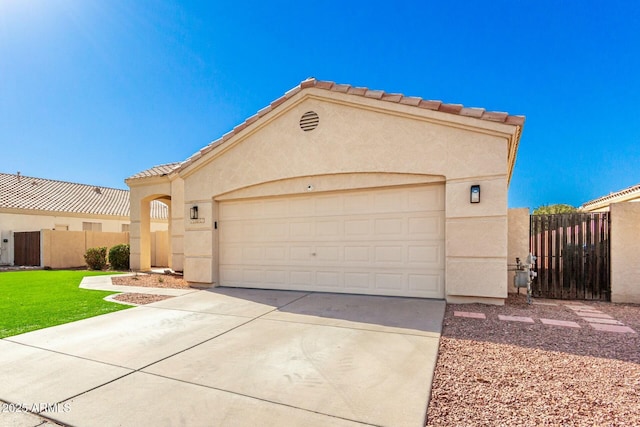 mediterranean / spanish-style home featuring a tiled roof, fence, concrete driveway, and stucco siding