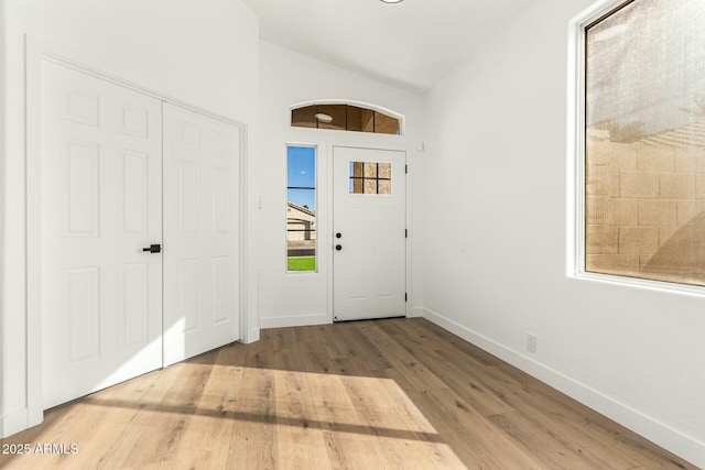 entrance foyer featuring lofted ceiling, wood finished floors, and baseboards