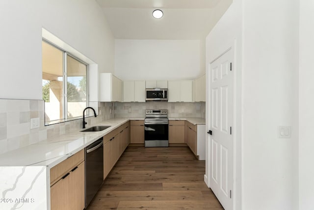 kitchen featuring light stone counters, appliances with stainless steel finishes, backsplash, and a sink