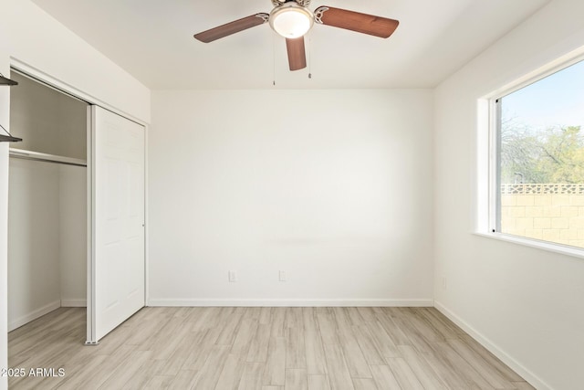 unfurnished bedroom with a closet, light wood-type flooring, a ceiling fan, and baseboards