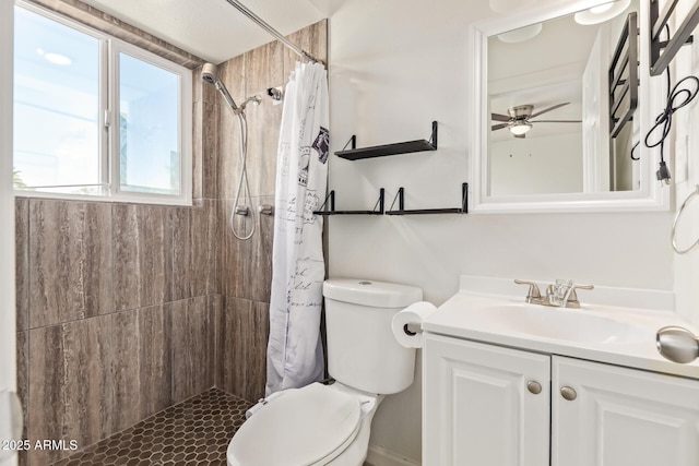 full bathroom with tiled shower, vanity, toilet, and a ceiling fan