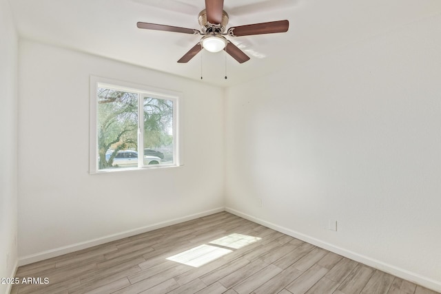 spare room with light wood-type flooring, a ceiling fan, and baseboards