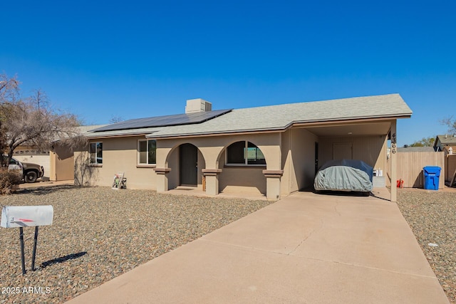 single story home with driveway, stucco siding, fence, and roof mounted solar panels