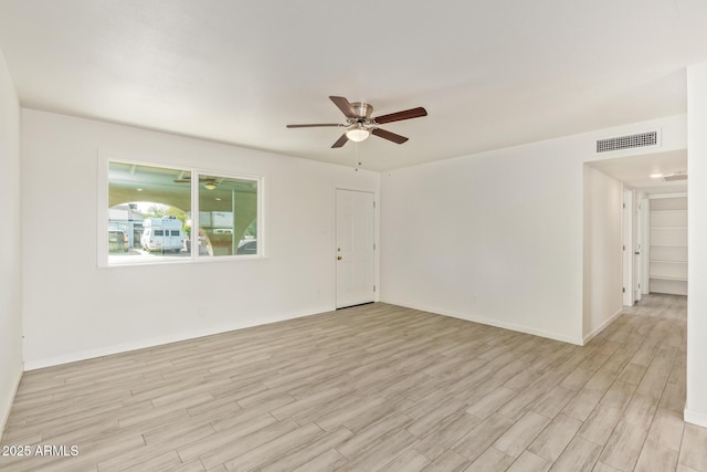 empty room featuring a ceiling fan, light wood-type flooring, visible vents, and baseboards