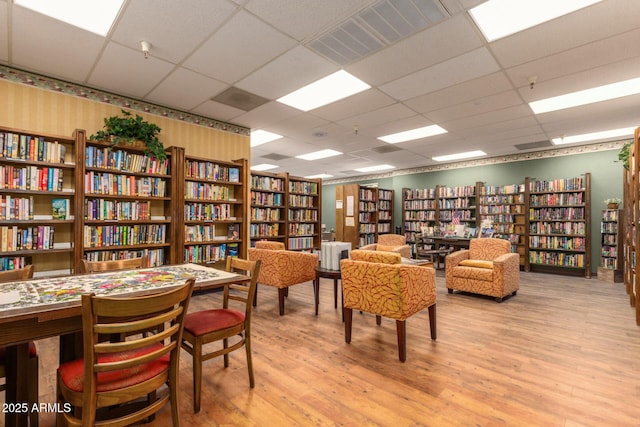 10330 W Thunderbird Blvd Unit C109, Sun City, AZ 85351 - sitting room featuring bookshelves, light wood-style flooring, wallpapered walls, and a drop ceiling