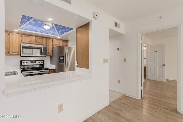 10330 W Thunderbird Blvd Unit C109, Sun City, AZ 85351 - kitchen with appliances with stainless steel finishes, light wood-style floors, light countertops, a peninsula, and recessed lighting
