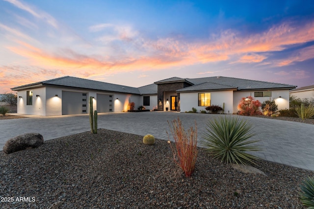 prairie-style home featuring a garage, decorative driveway, and stucco siding