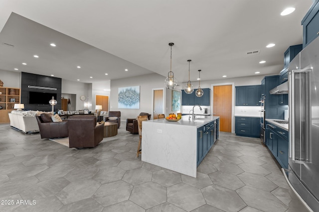 kitchen featuring light countertops, extractor fan, a kitchen island with sink, and blue cabinets