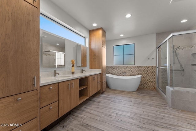 full bath with tile walls, a sink, a shower stall, and double vanity