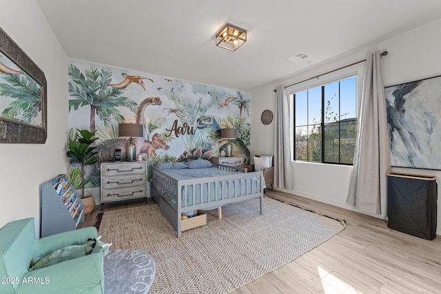 bedroom with light wood-style floors and visible vents