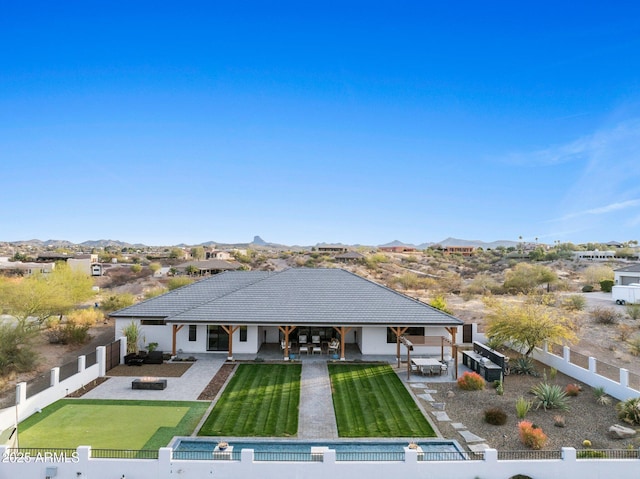 rear view of property with a yard, a patio area, a fenced backyard, and a mountain view