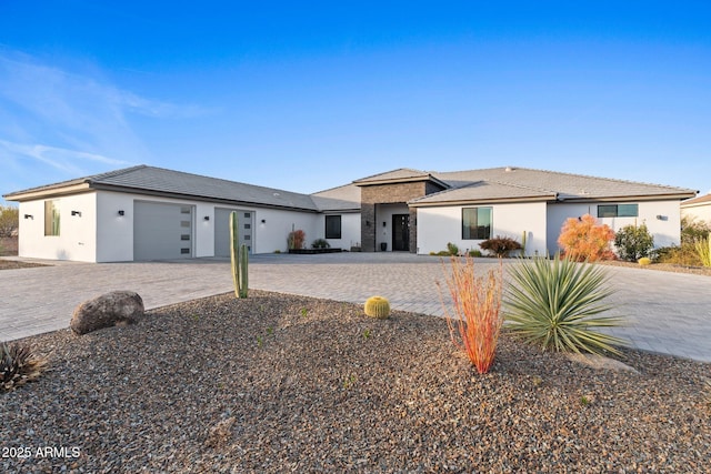 prairie-style house featuring a garage, decorative driveway, and stucco siding