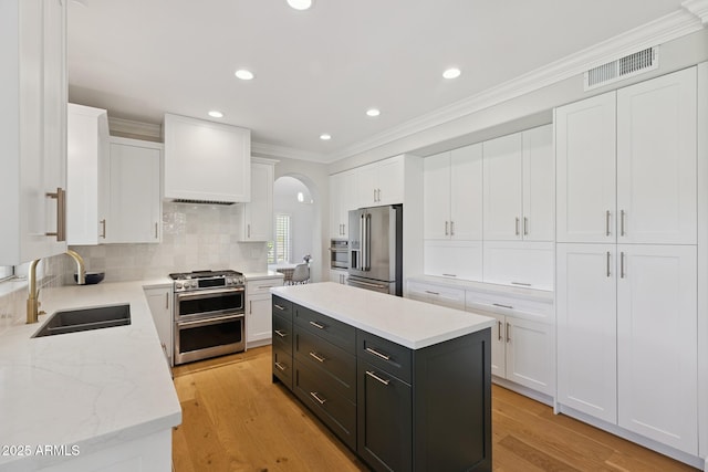 2258 N Gentry, Mesa, AZ 85213 - kitchen with appliances with stainless steel finishes, white cabinetry, arched walkways, dark cabinetry, and decorative backsplash