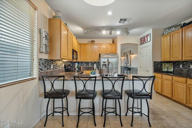 kitchen with sink, stainless steel fridge, a breakfast bar, light tile patterned floors, and stove