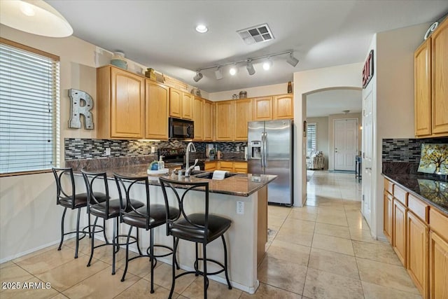 kitchen featuring light tile patterned floors, kitchen peninsula, black appliances, a breakfast bar, and sink