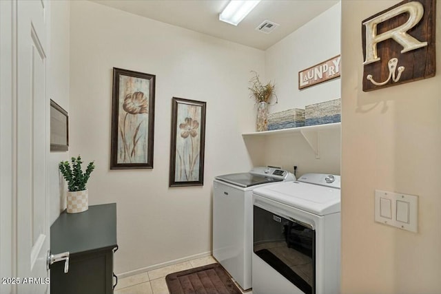 clothes washing area featuring light tile patterned floors and washer and dryer