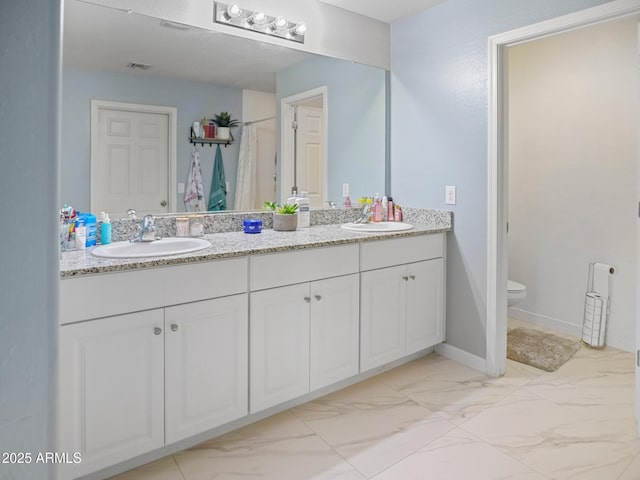 full bathroom with a sink, toilet, marble finish floor, and double vanity