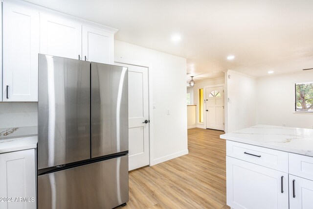 kitchen featuring white cabinets, stainless steel fridge, light stone countertops, and light hardwood / wood-style floors