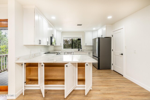 kitchen with light hardwood / wood-style flooring, kitchen peninsula, stainless steel refrigerator, white cabinetry, and light stone counters