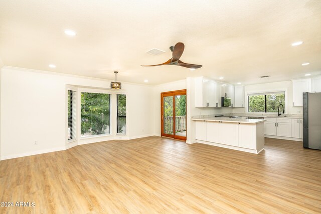 unfurnished living room with ceiling fan, ornamental molding, light hardwood / wood-style floors, and sink