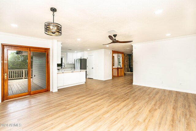 unfurnished living room with ceiling fan, crown molding, and light hardwood / wood-style flooring