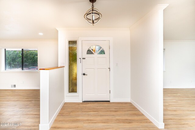 entryway with crown molding and light hardwood / wood-style floors