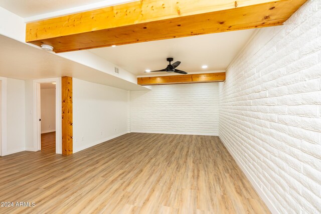 spare room featuring ceiling fan, light hardwood / wood-style floors, and brick wall