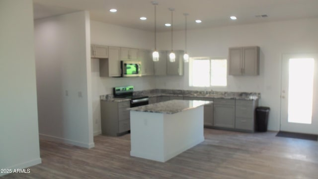 kitchen with a kitchen island, stainless steel microwave, gray cabinets, and electric stove