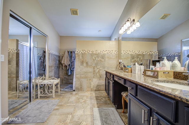 bathroom with vanity, tile walls, and walk in shower