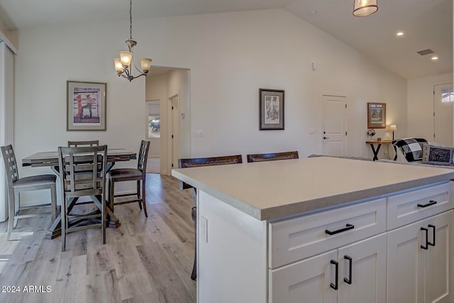 kitchen featuring a center island, an inviting chandelier, white cabinets, pendant lighting, and light hardwood / wood-style flooring