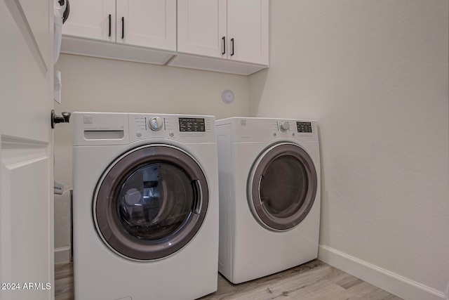 washroom featuring cabinets, washer and dryer, and light hardwood / wood-style floors