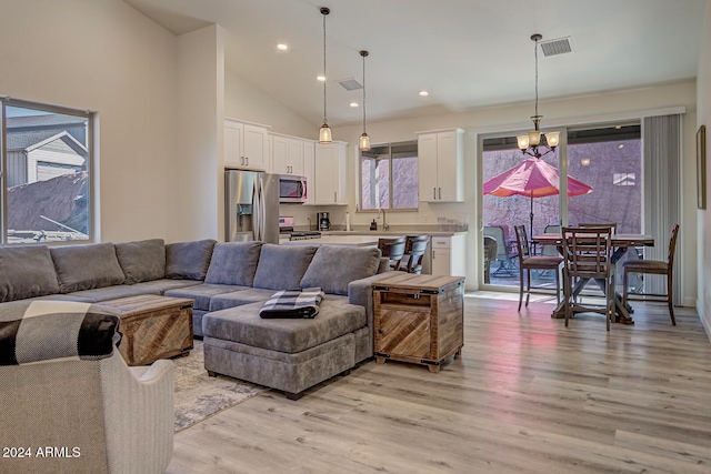 living room featuring high vaulted ceiling, light wood-type flooring, and sink