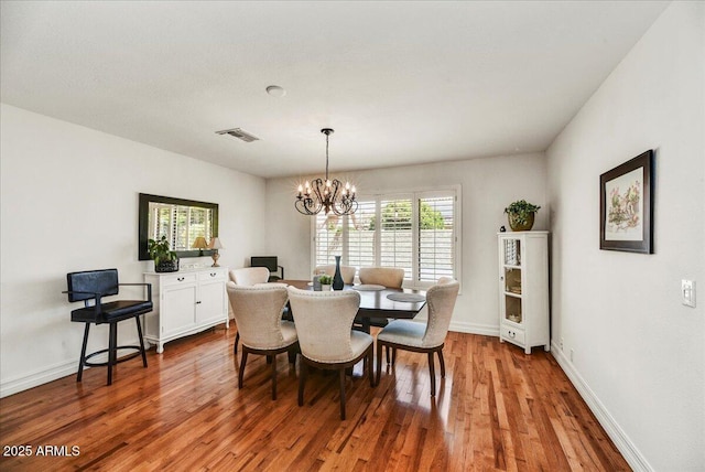 dining room with visible vents, baseboards, wood finished floors, and a chandelier