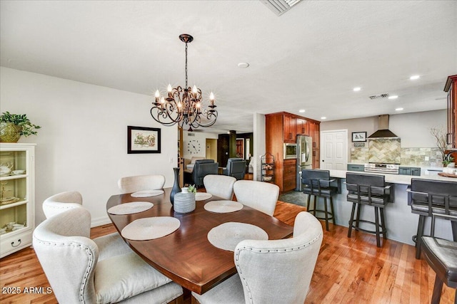dining space with recessed lighting, a chandelier, light wood finished floors, and visible vents
