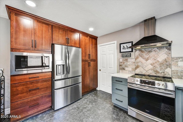 kitchen featuring light countertops, stainless steel appliances, decorative backsplash, and wall chimney exhaust hood