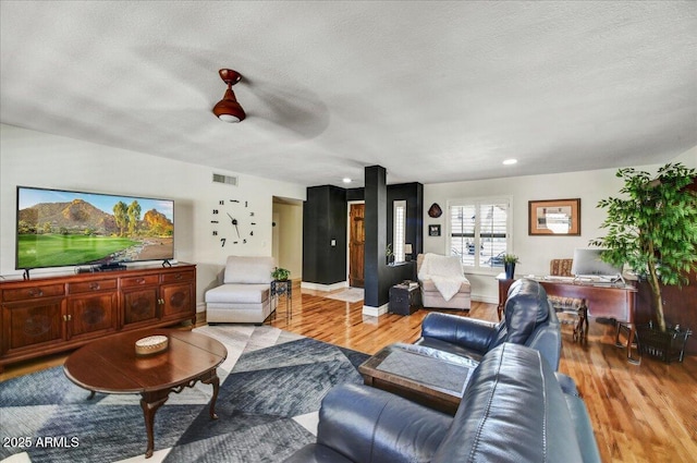 living area featuring visible vents, a textured ceiling, and wood finished floors