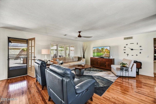 living area with baseboards, ceiling fan, hardwood / wood-style floors, and visible vents