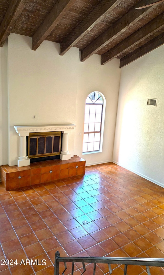 unfurnished living room featuring visible vents, a tile fireplace, wood ceiling, beamed ceiling, and dark tile patterned floors