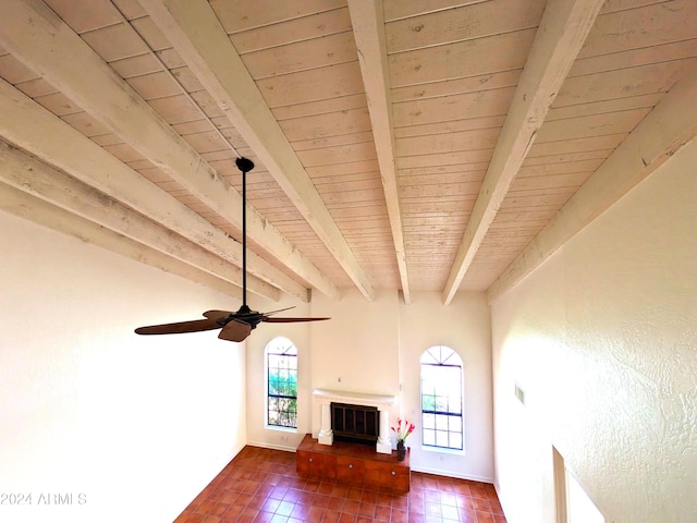 unfurnished living room featuring a glass covered fireplace, beam ceiling, wooden ceiling, and plenty of natural light