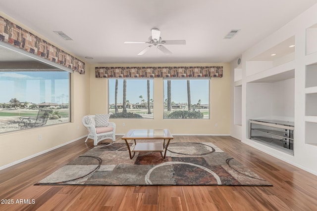 sitting room featuring built in features, visible vents, baseboards, and wood finished floors