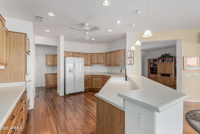 kitchen with visible vents, dark wood-type flooring, a peninsula, white fridge with ice dispenser, and a sink