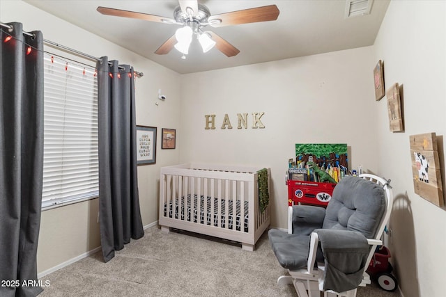 carpeted bedroom featuring ceiling fan and a crib