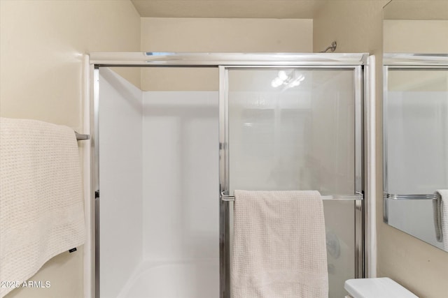 bathroom featuring a shower with shower door and toilet